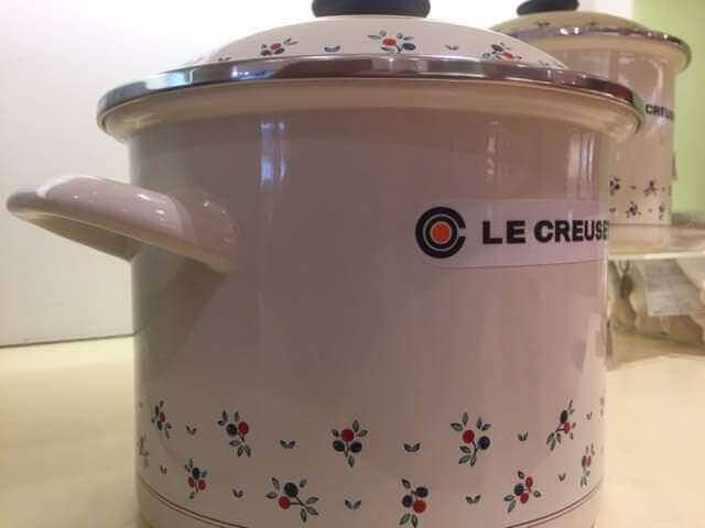 Large Stock pot made by Le Creuset. (Stock pot is white with red flowers at the base and on the lid. Pot has Le Creuset Logo)