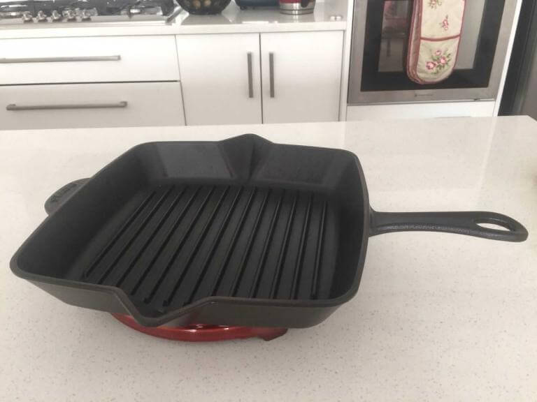 Black Staub grill pan on cherry red Staub trivet.