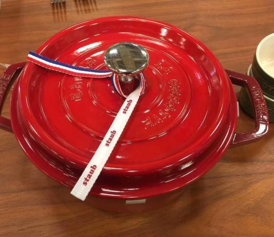 New Red Staub Dutch oven on a wooden table.