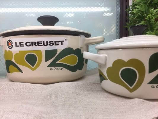 Two white Le Creuset dutch ovens with black knobs.