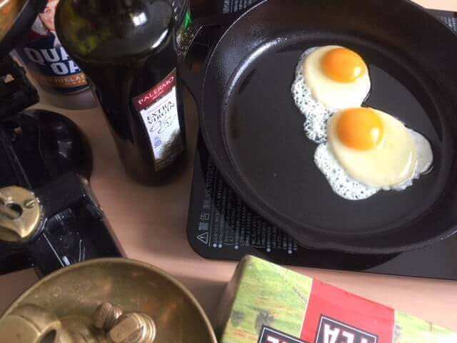 Why use a cast iron skillet? A photo of two eggs frying in a cast iron skillet.