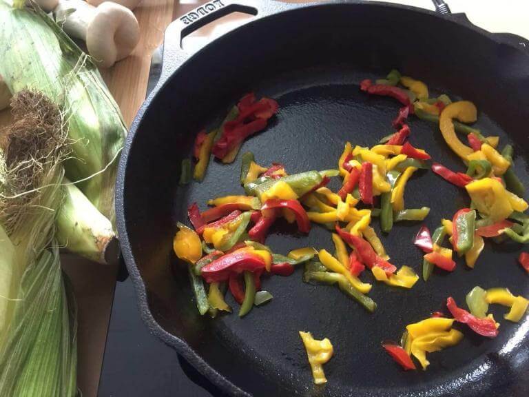 Lodge manufacturing Company skillet. In the cast-iron skillet are vegetables being cooked.