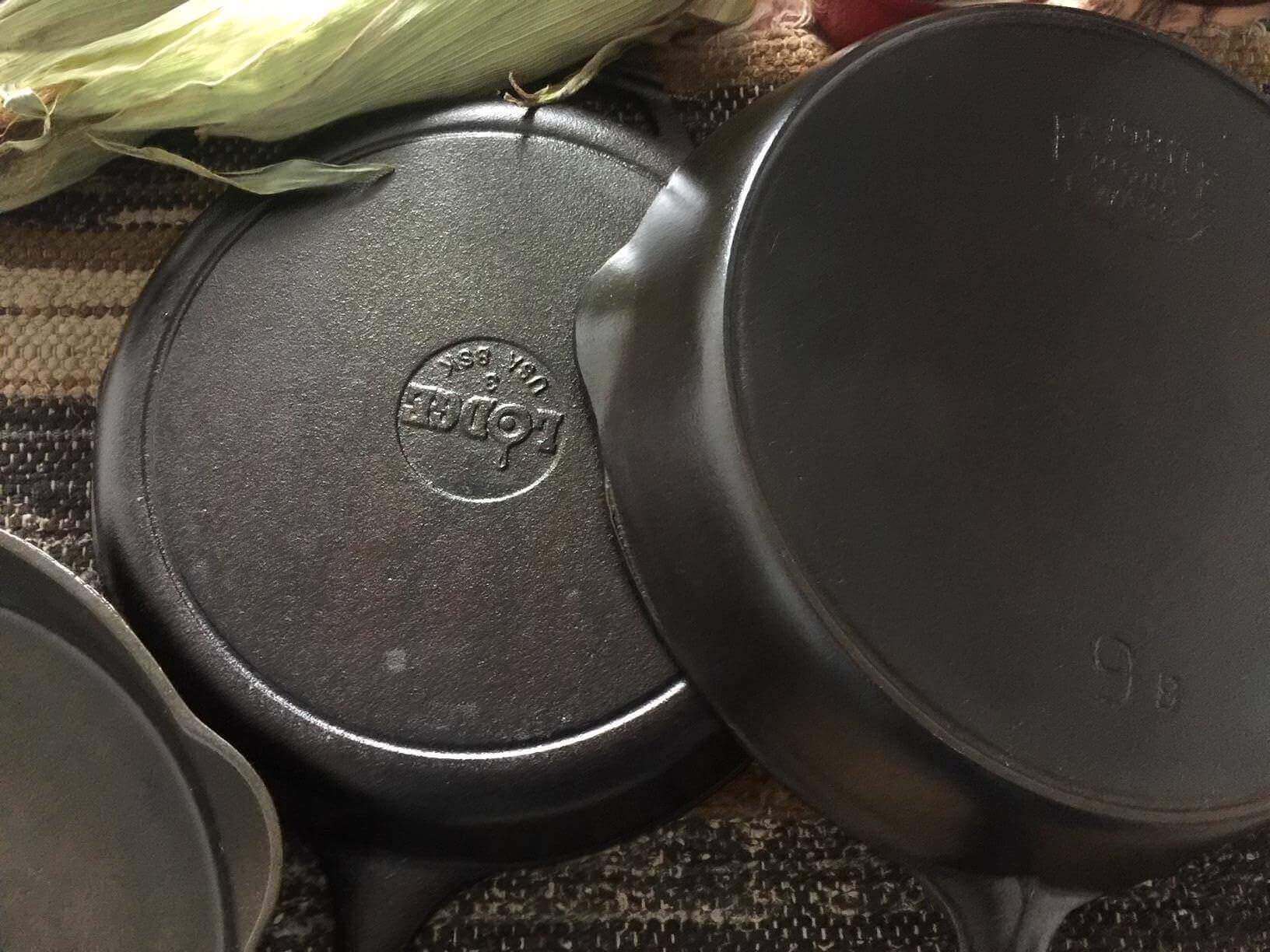 Two old vintage cast iron skillets with a new cast iron skillet.